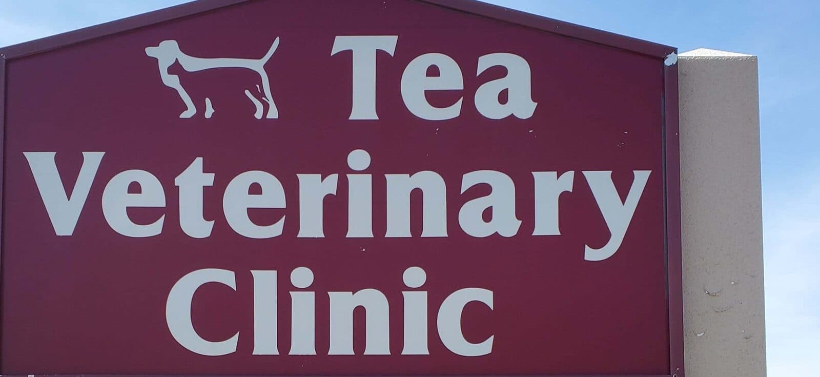 The Tea Veterinary Clinic road sign panel: white letters and the pointer-dog silhouette on maroon