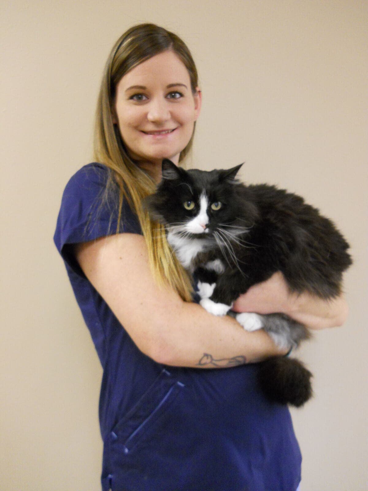 Kendra in navy scrubs holding a fluffy tuxedo cat