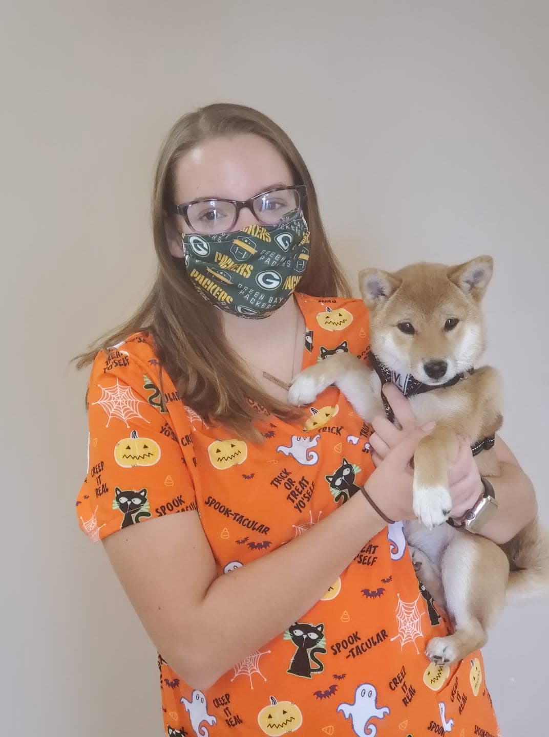 Shiba inu puppy held by a staff member in Halloween scrubs