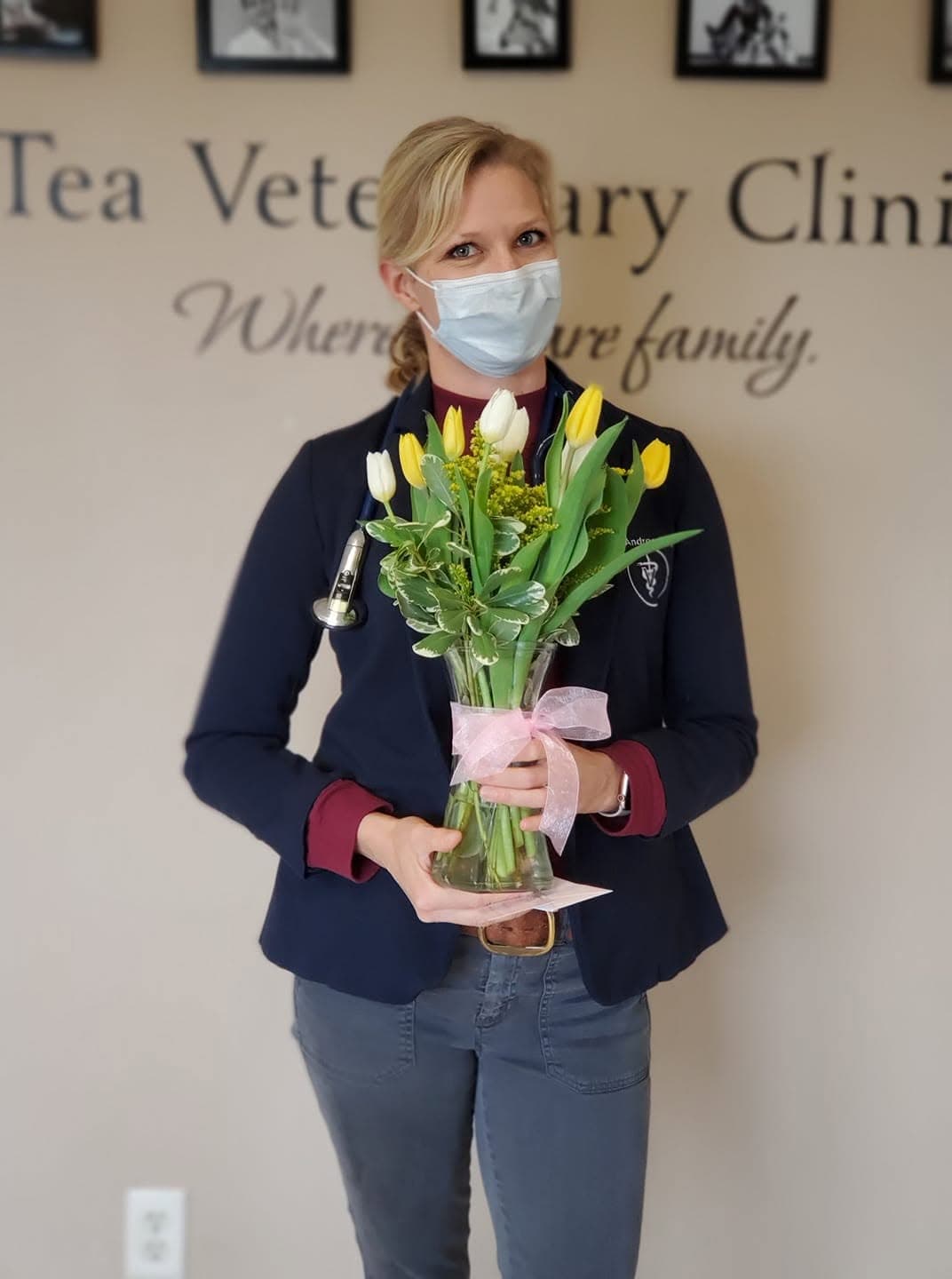 A Tea Vet doctor with a bouquet of tulips under the reception wall lettering